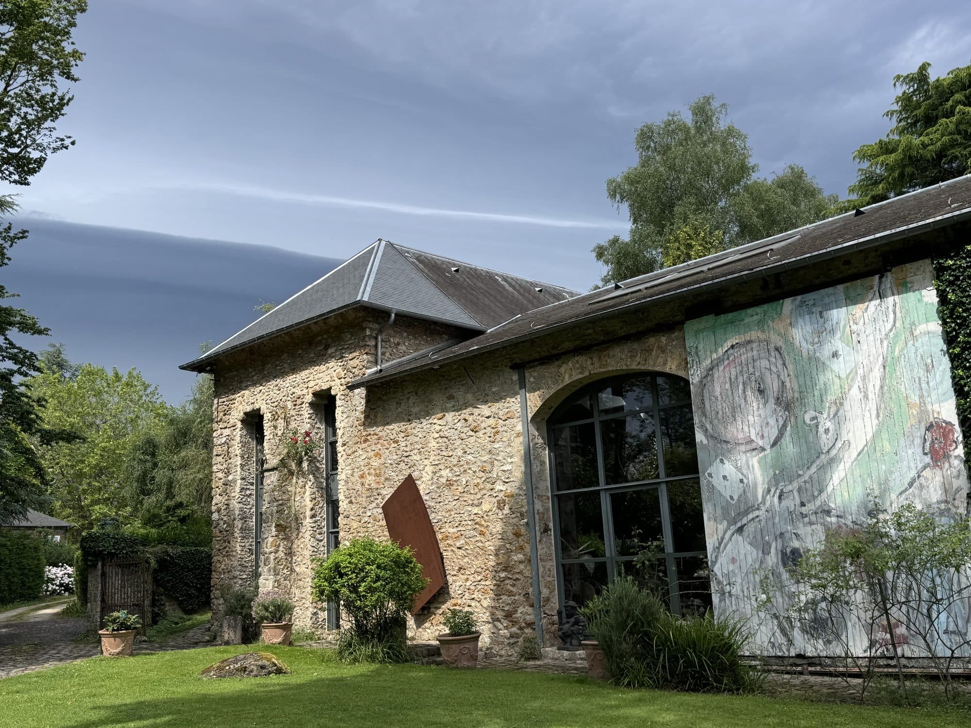 Le bâtiment, façade de pierre et fresque, vu du parc