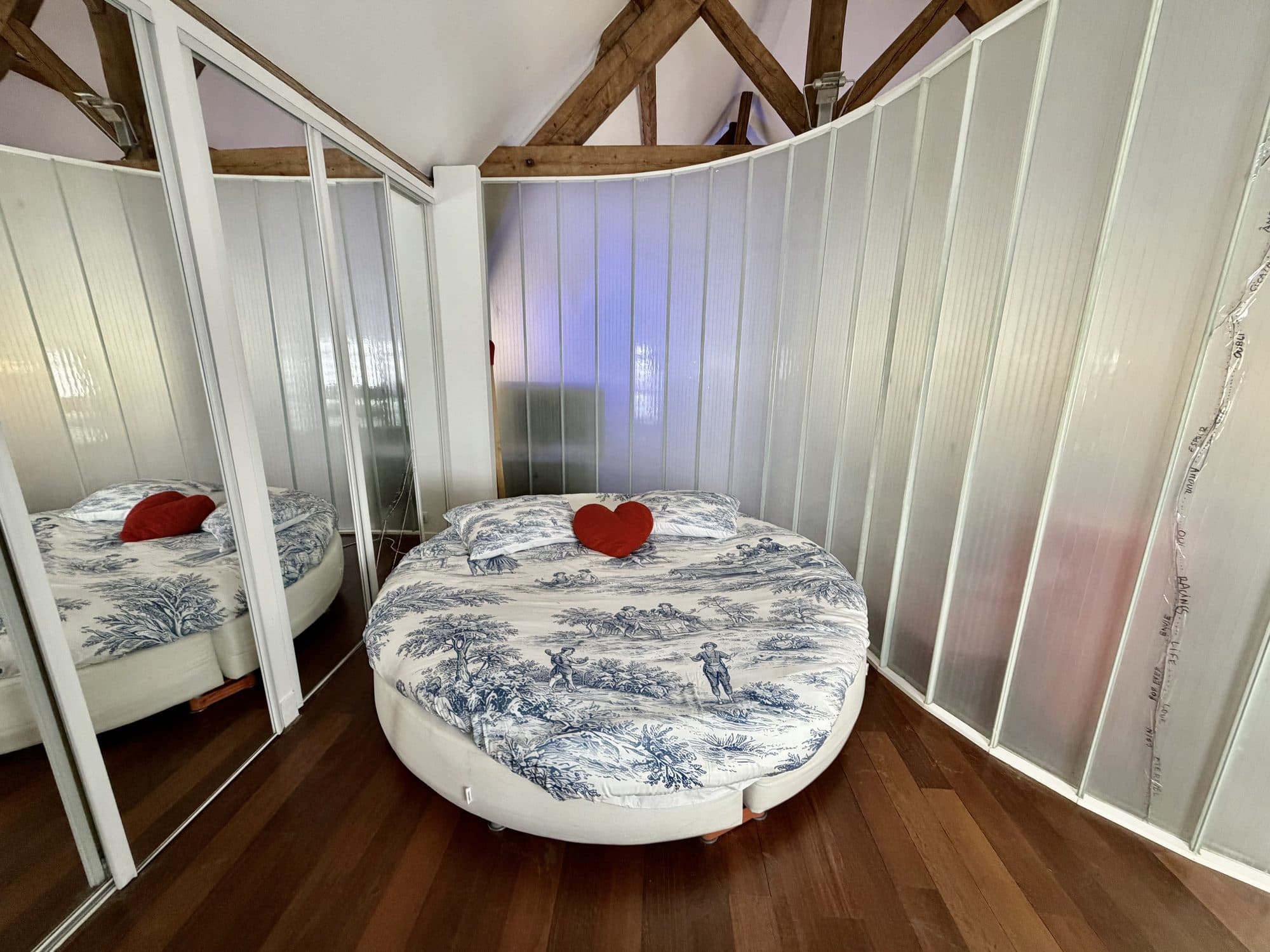 Le lit rond de la chambre, derrière sa cloison de verre