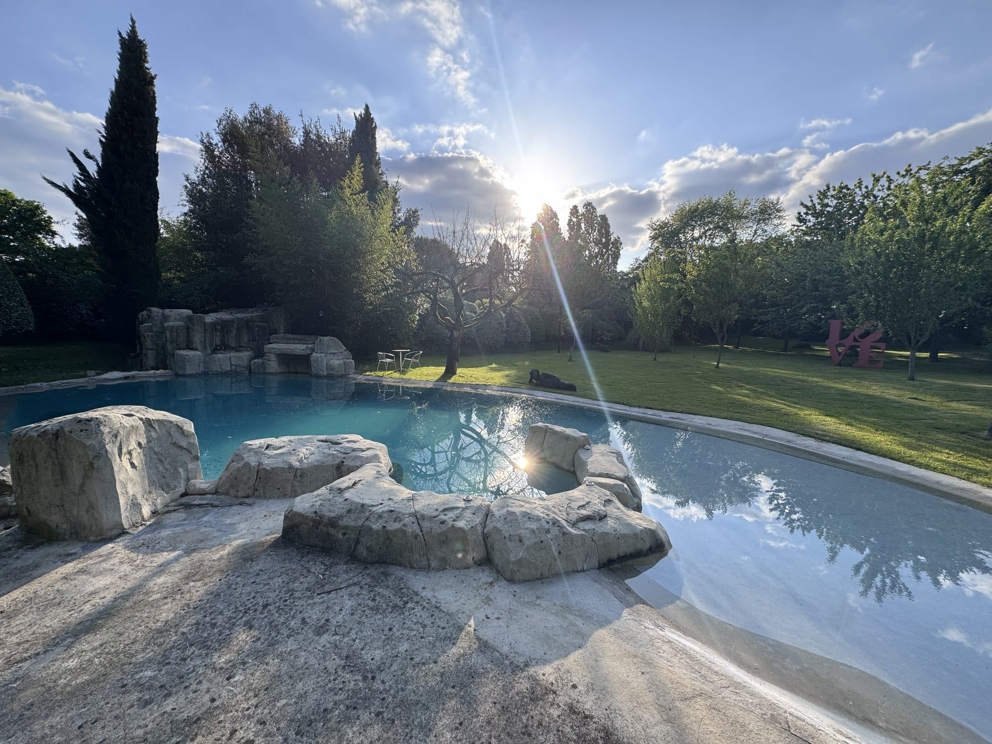 La piscine au soleil, bordée de rochers, dans le parc